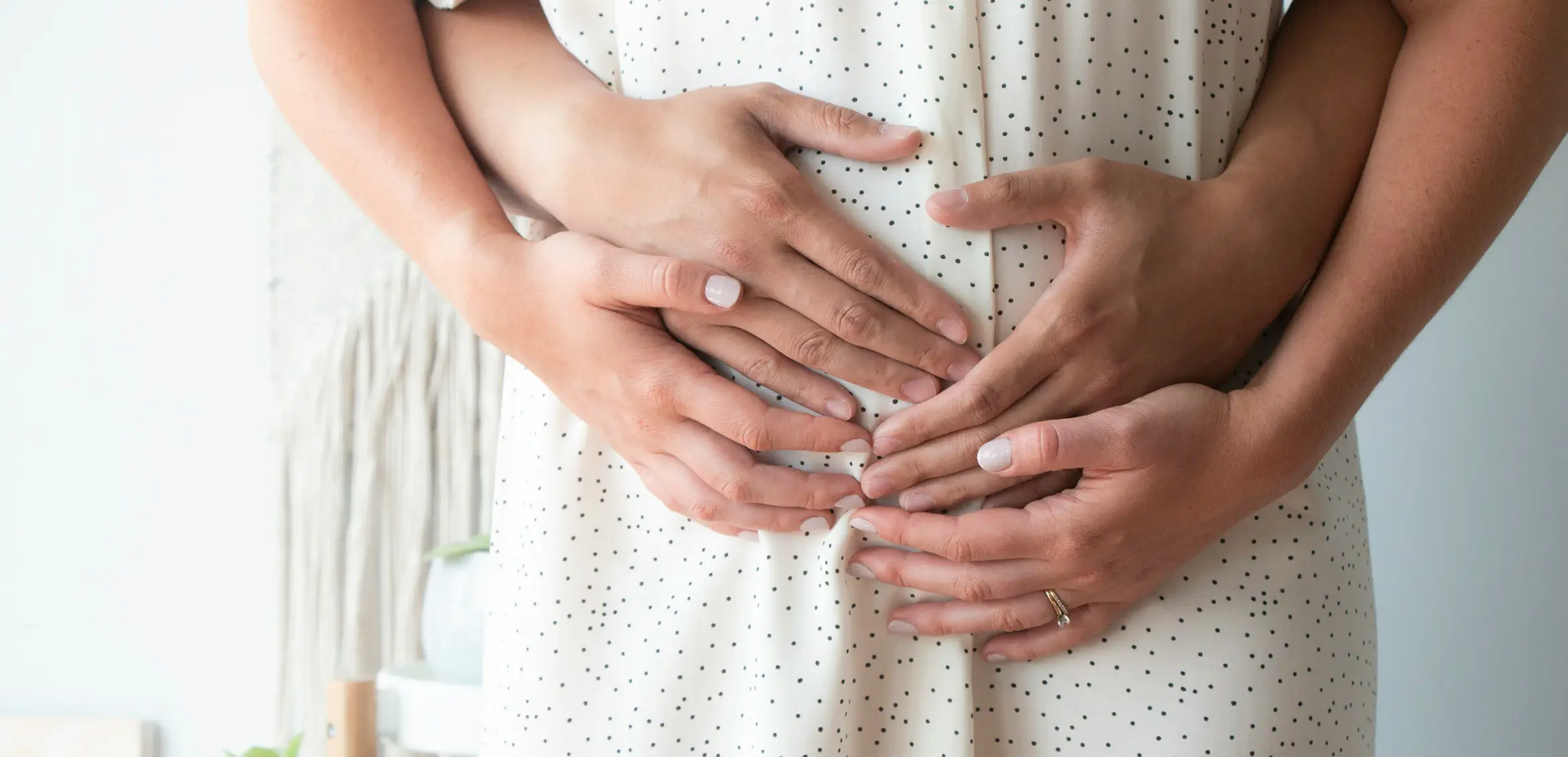 Same sex couple holding woman's pregnant belly