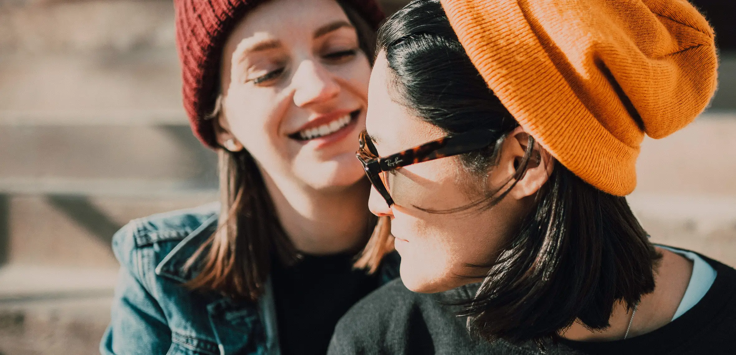 Two people smiling wearing beanie hats