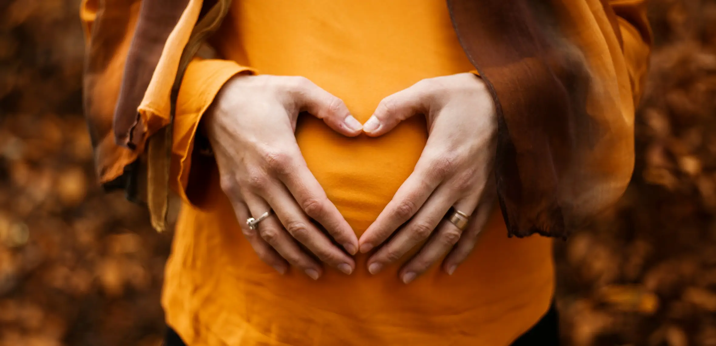Woman holding belly making a heart shape